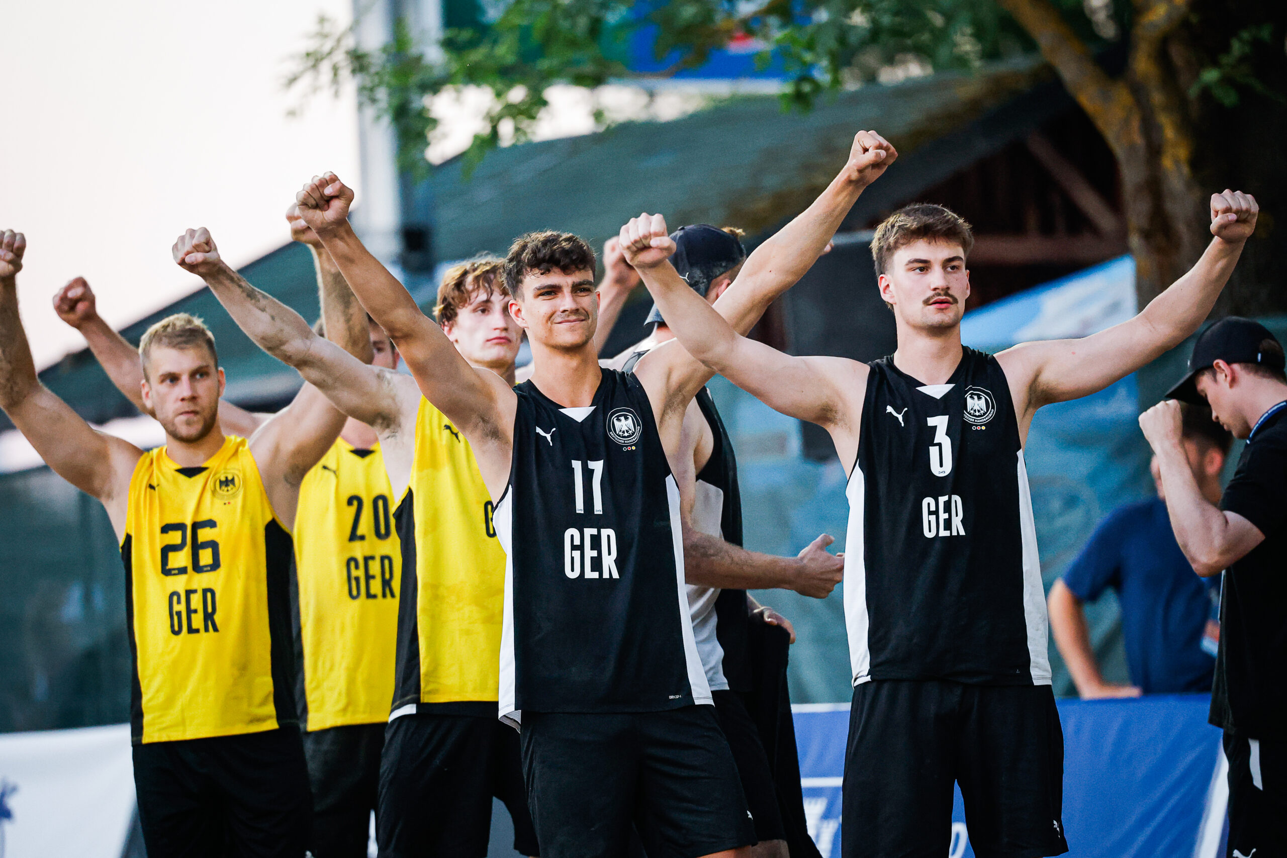 A group of athletes in German national team jerseys raise their fists in unison, displaying unity and determination.